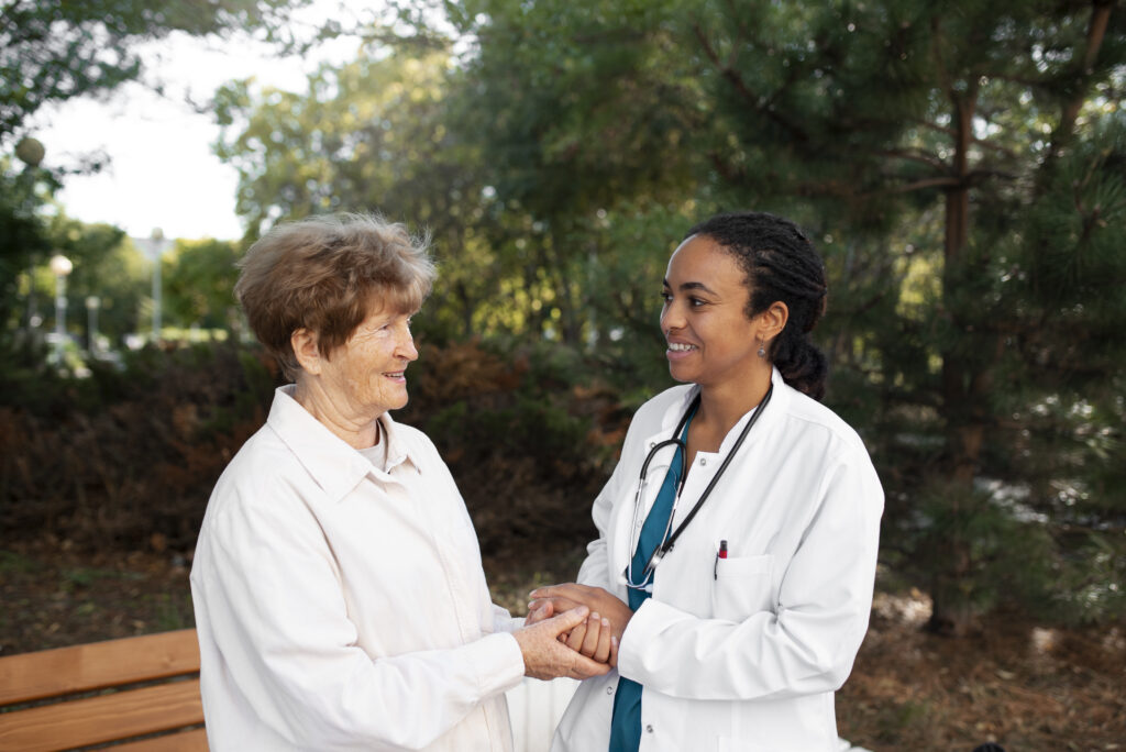 Médica e senhora idosa conversando ao ar livre de mãos dadas