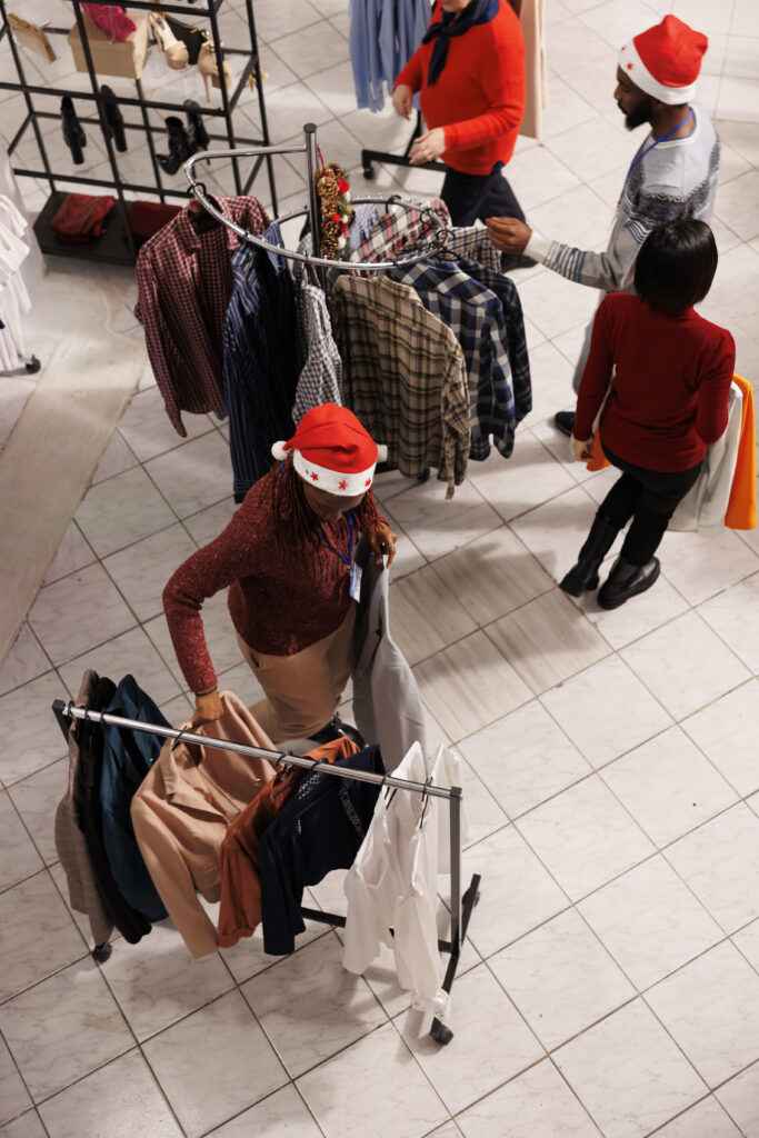 Pessoas fazendo compras com gorros de natal em uma loja de roupas