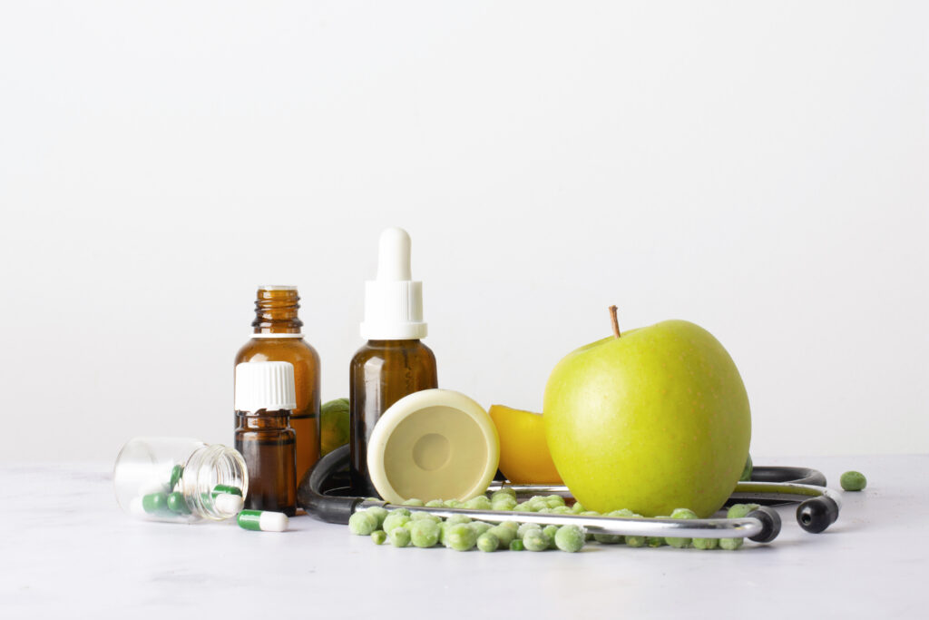 Imagem com medicações, estetoscópio e maçã sobre uma mesa.